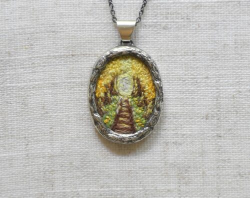 Pendentif avec un chemin de fer brodé de couleur jaune fabriqué par Rosalie Lambert-Sarrazin.