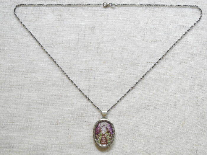 Pendentif avec un chemin de fer brodé de couleur mauve et chainette de 18’’ fabriqué par Rosalie Lambert-Sarrazin.