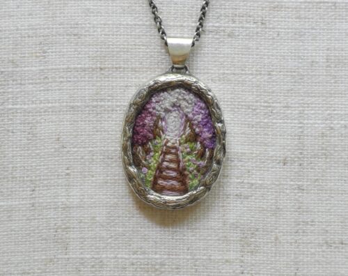 Pendentif avec un chemin de fer brodé de couleur mauve fabriqué par Rosalie Lambert-Sarrazin.