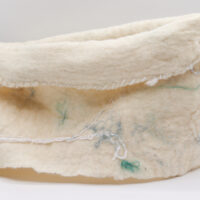 Photo d'un cache-cou feutré artisanal de couleur blanche, fait à la main avec des détails subtils de fibres colorées. Doux et confortable, idéal pour l'hiver.