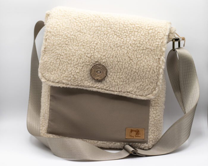 Photo d'un sac à main éco-responsable avec un rabat en tissu effet mouton blanc, une sangle ajustable beige et des détails en cuir. Ce sac allie style et confort.