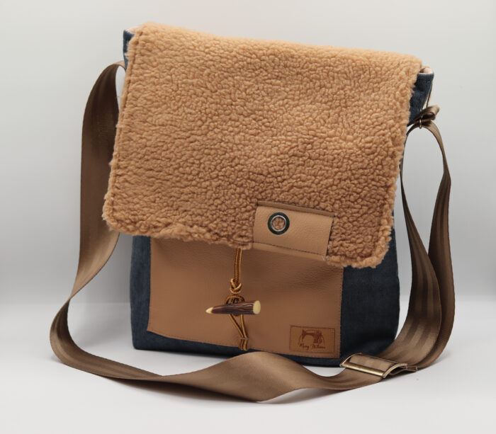 Photo d'un sac à main éco-responsable avec un rabat en tissu effet mouton brun, une sangle ajustable marron et des détails en cuir. Ce sac allie style et durabilité.